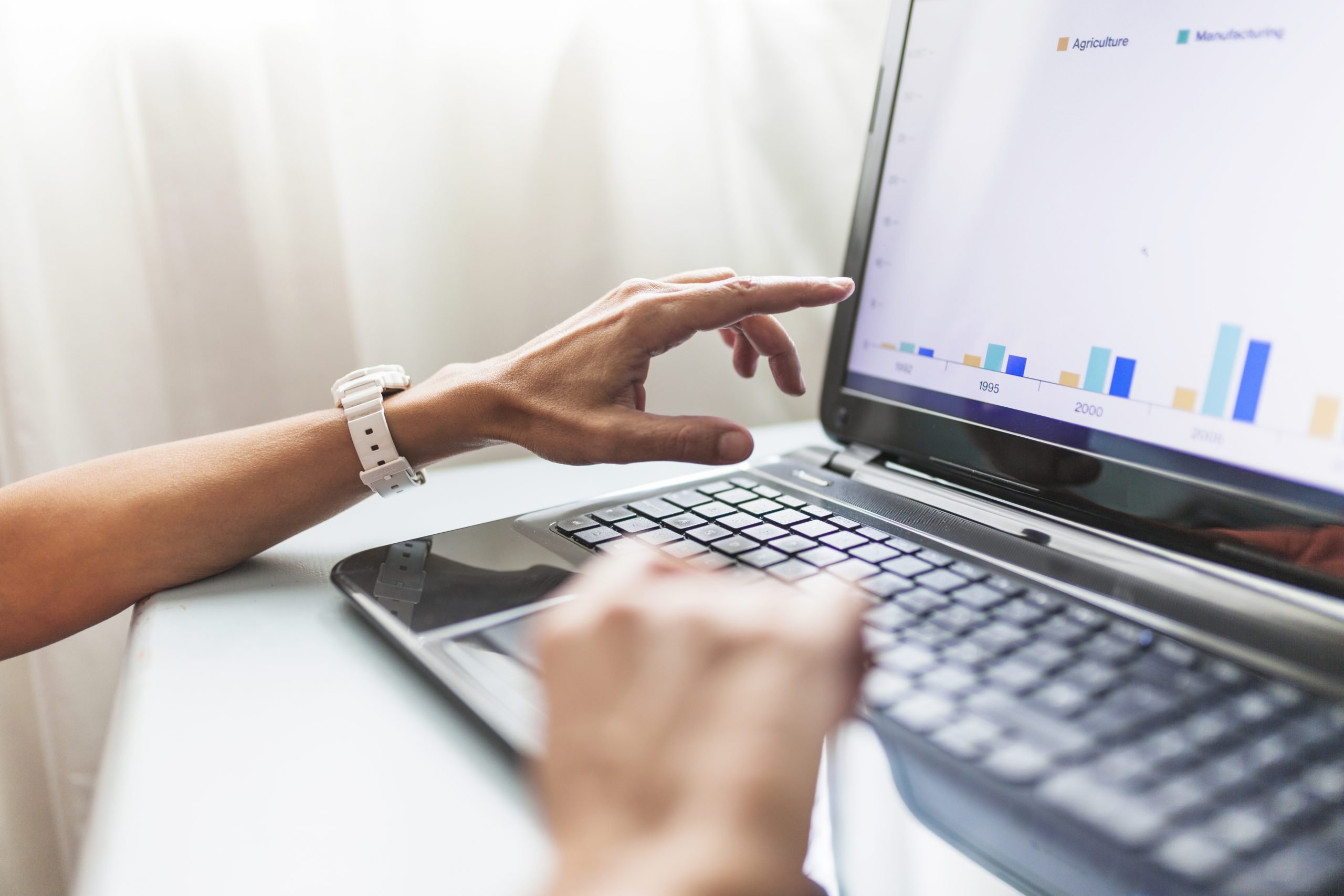 Keene Marketing Agency A person analyzing a bar chart on a laptop screen while pointing and typing.