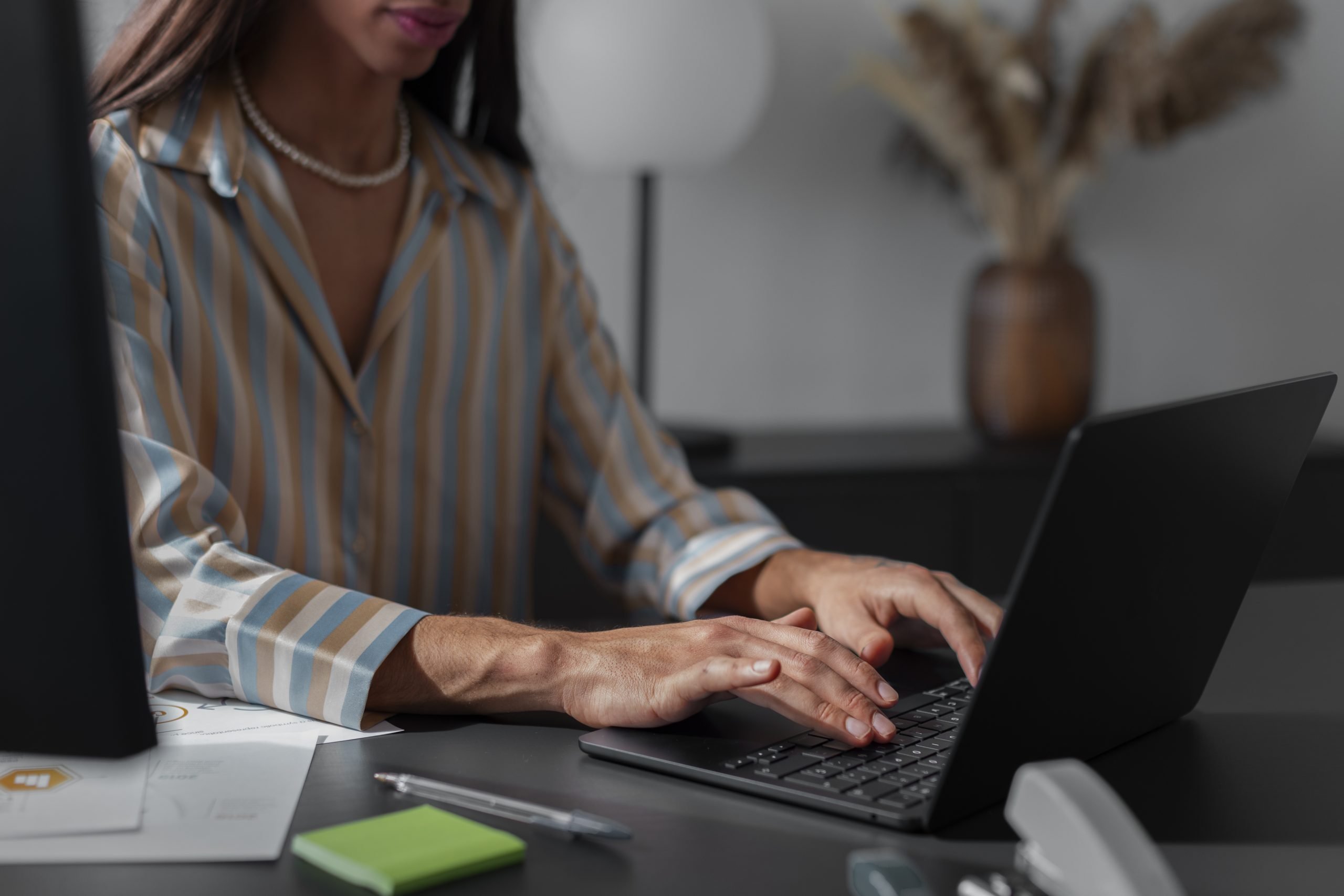 Keene Marketing Agency Woman in a striped shirt typing on a laptop in an office setting.
