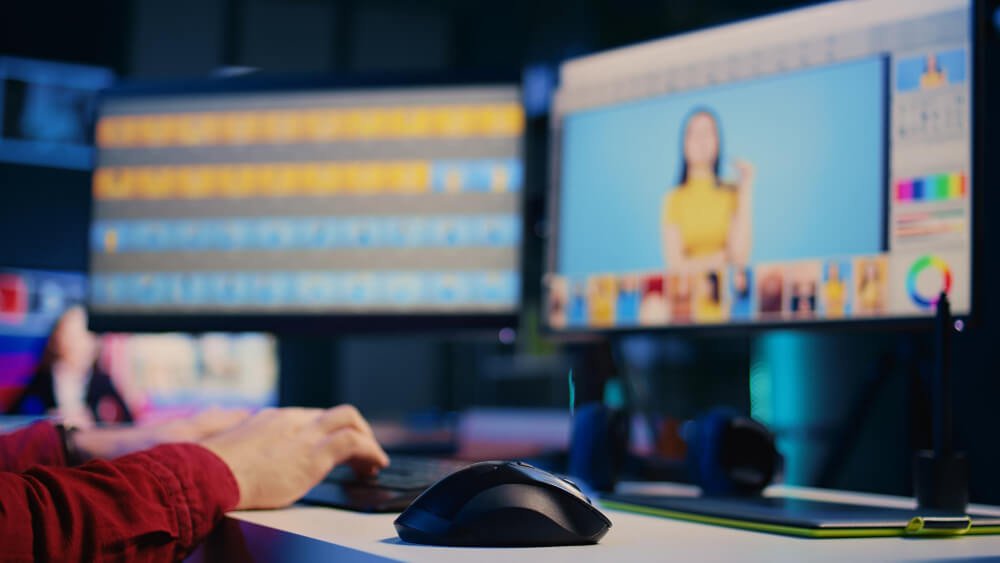 New Hampshire         Description: Person editing a photo on a desktop computer with dual monitors in a dimly lit room. The left monitor displays a timeline, and the right monitor shows an image of a woman in yellow top, almost as if he's following a step-by-step guide for creating motion graphics. Marketing Agency