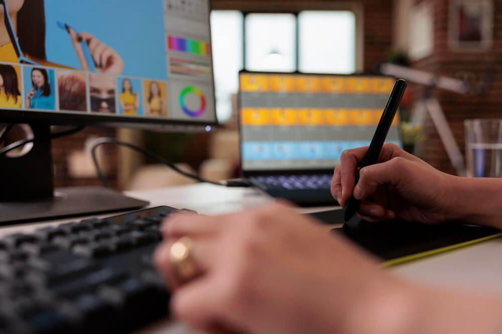 New Hampshire In the digital era, a person uses a stylus on a graphic tablet to edit an image of a person on a computer screen, with another screen showcasing multiple image thumbnails in the background—hallmarks of any professional graphic design agency. Marketing Agency