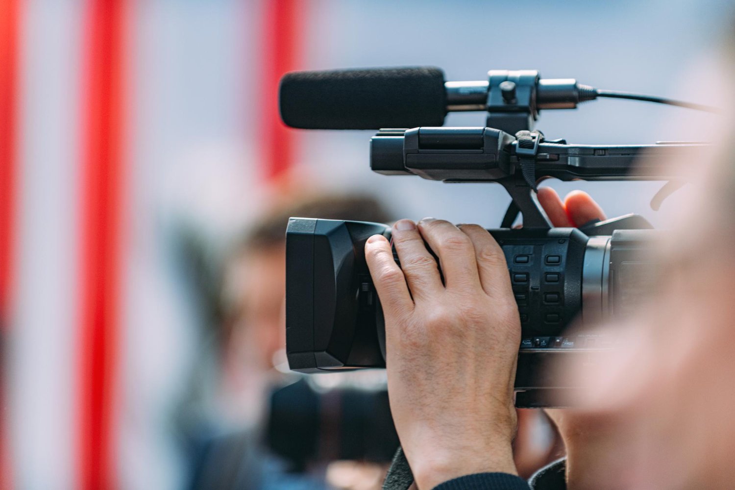 New Hampshire Close-up of a person's hands operating a professional video camera with a microphone attached, embracing the spirit of capturing perfect moments akin to the precision seen in the Olympics. Marketing Agency