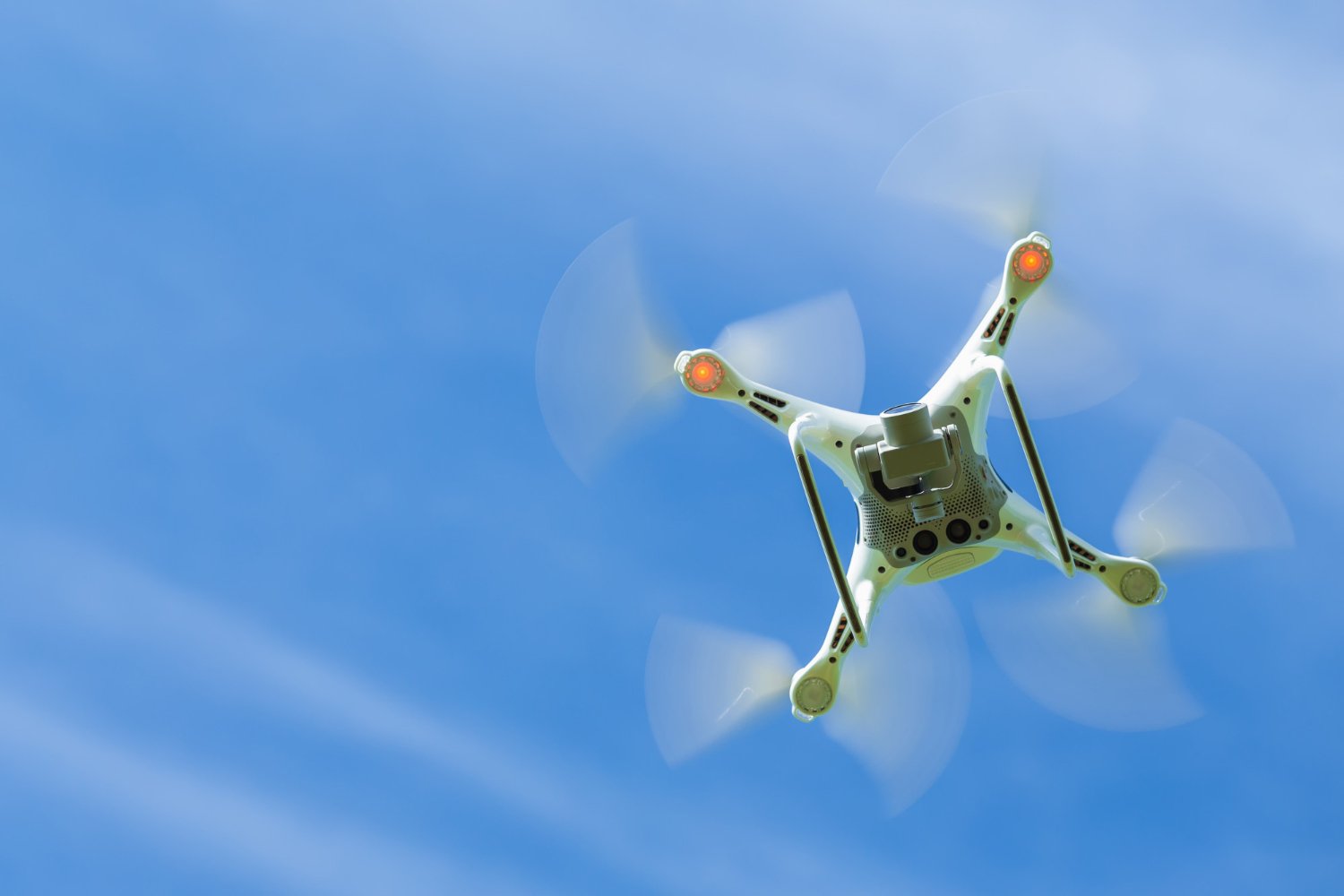 New Hampshire A white quadcopter drone flying in the sky with its propellers spinning, elevating your brand by capturing stunning aerial footage for professional video production. Marketing Agency
