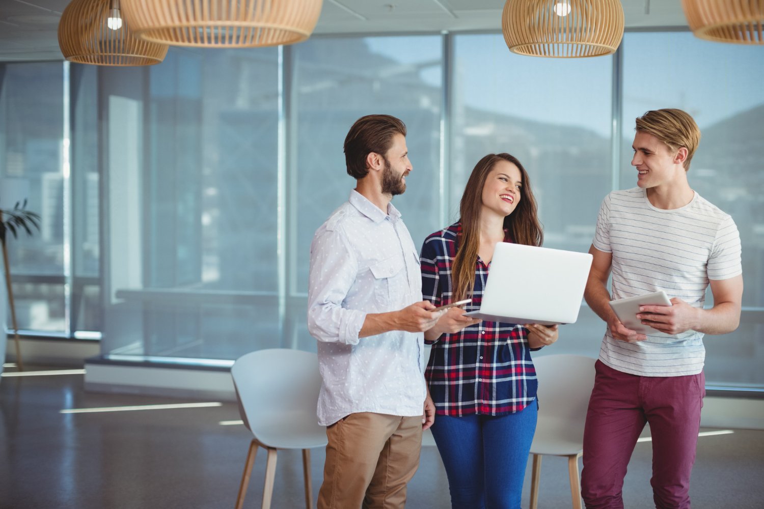 New Hampshire Three people engaged in conversation in a modern office space, one holding a laptop, another person holding a tablet. It's just another day in the life at our full-service marketing agency, offering you a glimpse behind the scenes of how we innovate and collaborate to bring ideas to life. Marketing Agency
