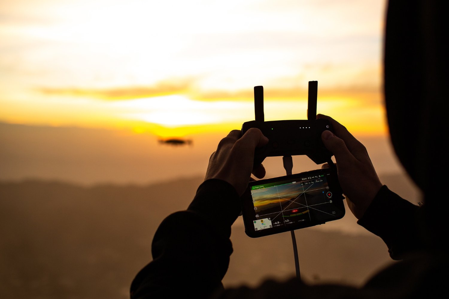 New Hampshire The person operates a drone with a handheld controller during sunset, as the horizon and sky display warm colors in the background—an ideal moment for capturing stunning visuals that can elevate small businesses' video marketing trends for 2024. Marketing Agency
