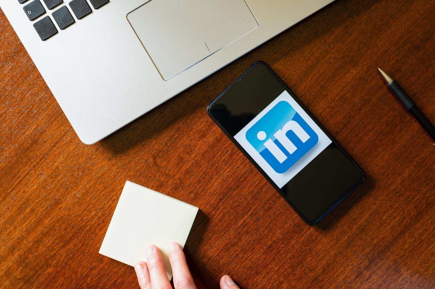 New Hampshire A hand holding a sticky note next to a phone, emphasizing LinkedIn marketing strategies for small businesses. Marketing Agency