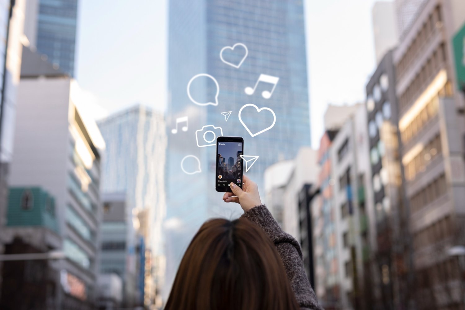 New Hampshire A person is holding up a smartphone towards tall buildings, with digital icons like hearts and music notes appearing around the phone, capturing the latest social media trends. Marketing Agency