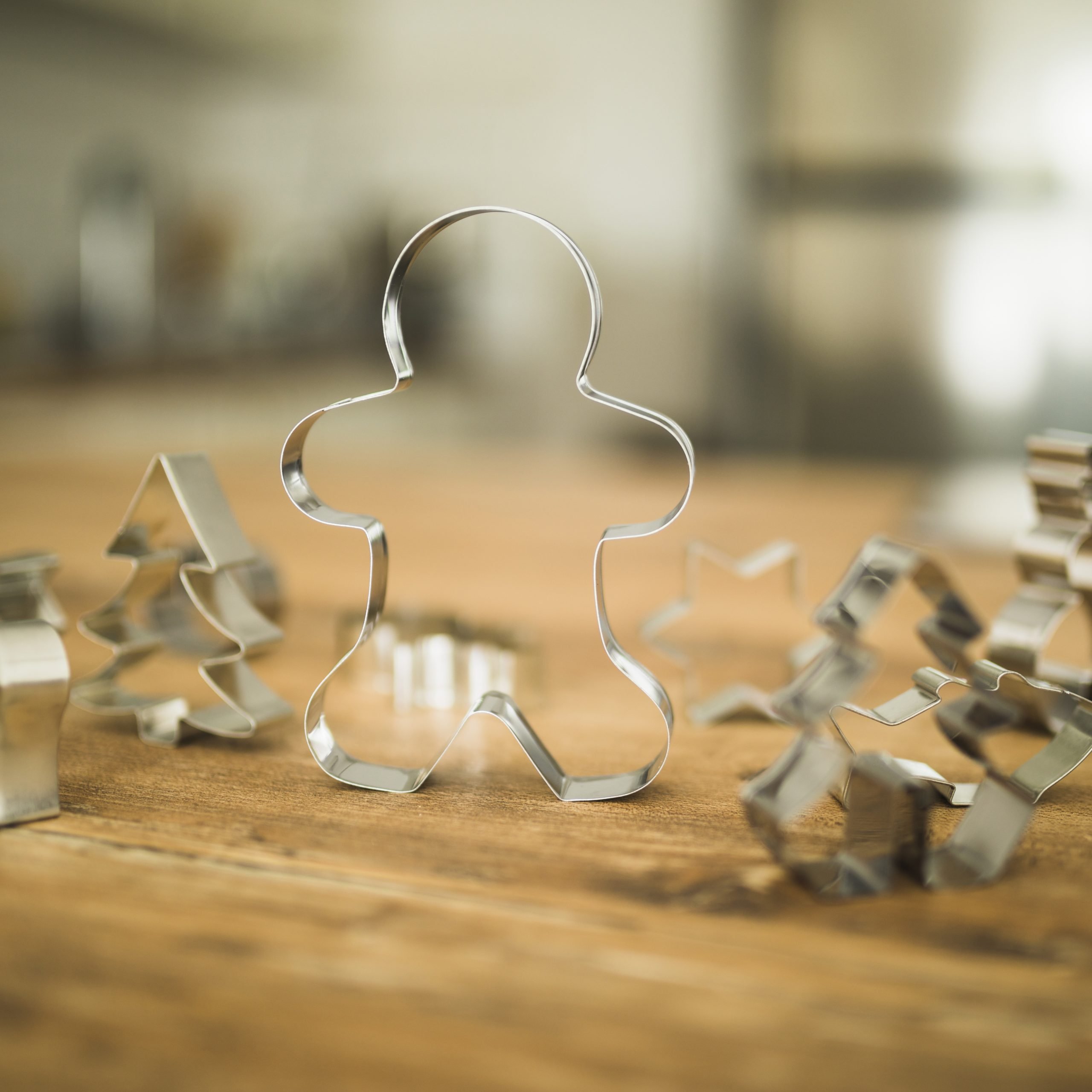 New Hampshire Close-up of several metal cookie cutters, including a gingerbread person, a Christmas tree, and a star, placed on a wooden surface. This cozy scene evokes the charm of New England holidays celebrated by small business owners. Marketing Agency