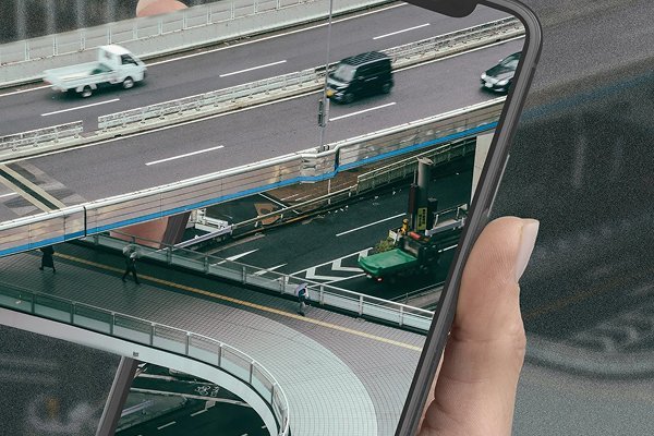 New Hampshire A hand holds a smartphone, displaying a perfectly aligned image of elevated highways and moving vehicles—an ideal visual for an asphalt company’s comprehensive guide that matches the real-life scene in the background. Marketing Agency