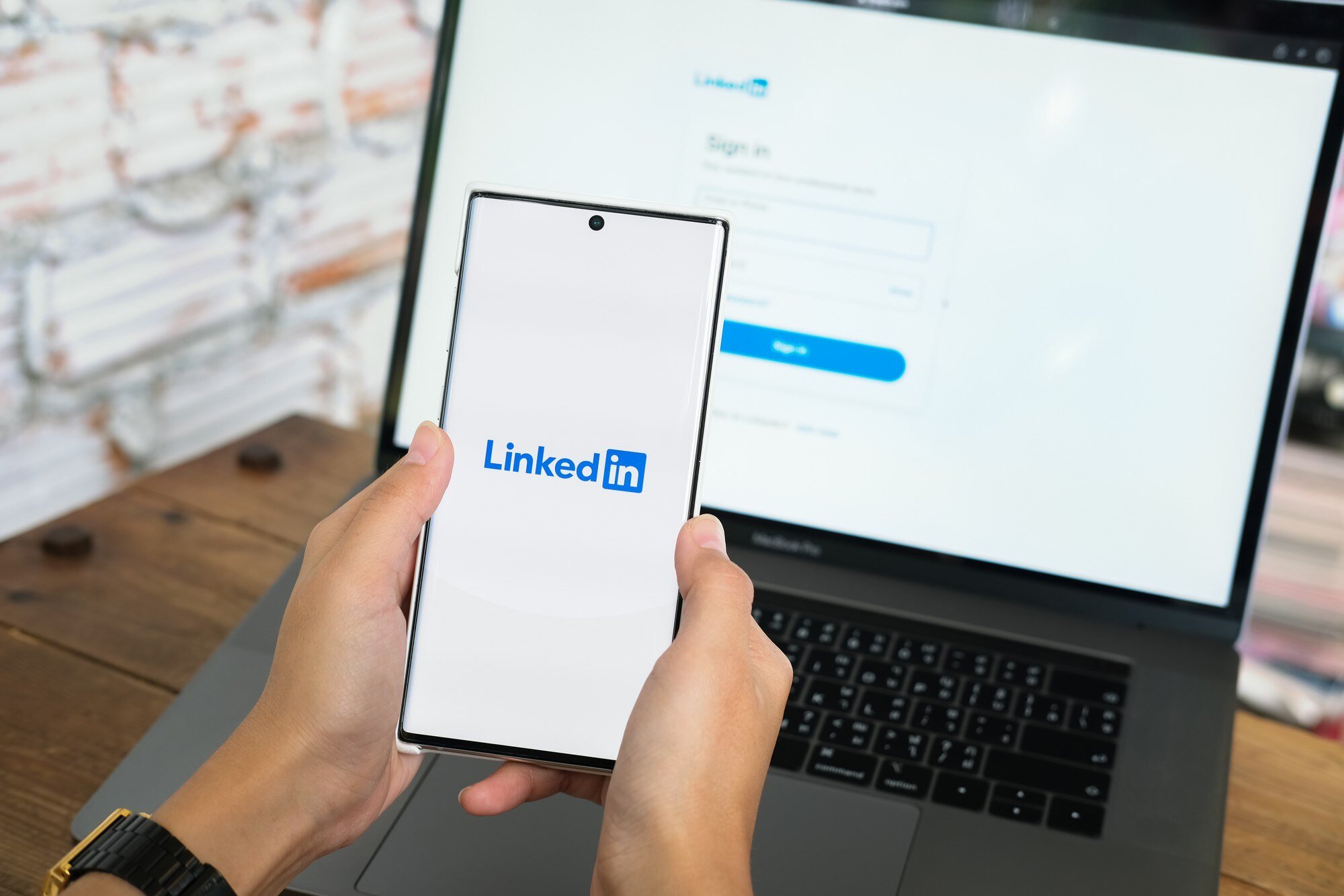 New Hampshire A business owner holding a smartphone displaying the LinkedIn logo in front of a laptop screen showing the LinkedIn sign-in page, emphasizing the platform's utility for performance marketing strategies. Marketing Agency