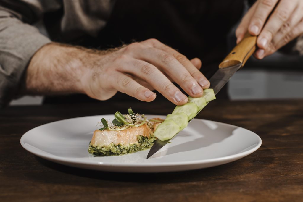 New Hampshire A person arranging sliced cucumber on a plate with salmon and green garnish, skillfully crafting a dish that embodies the essence of local marketing ideas for restaurants. Marketing Agency