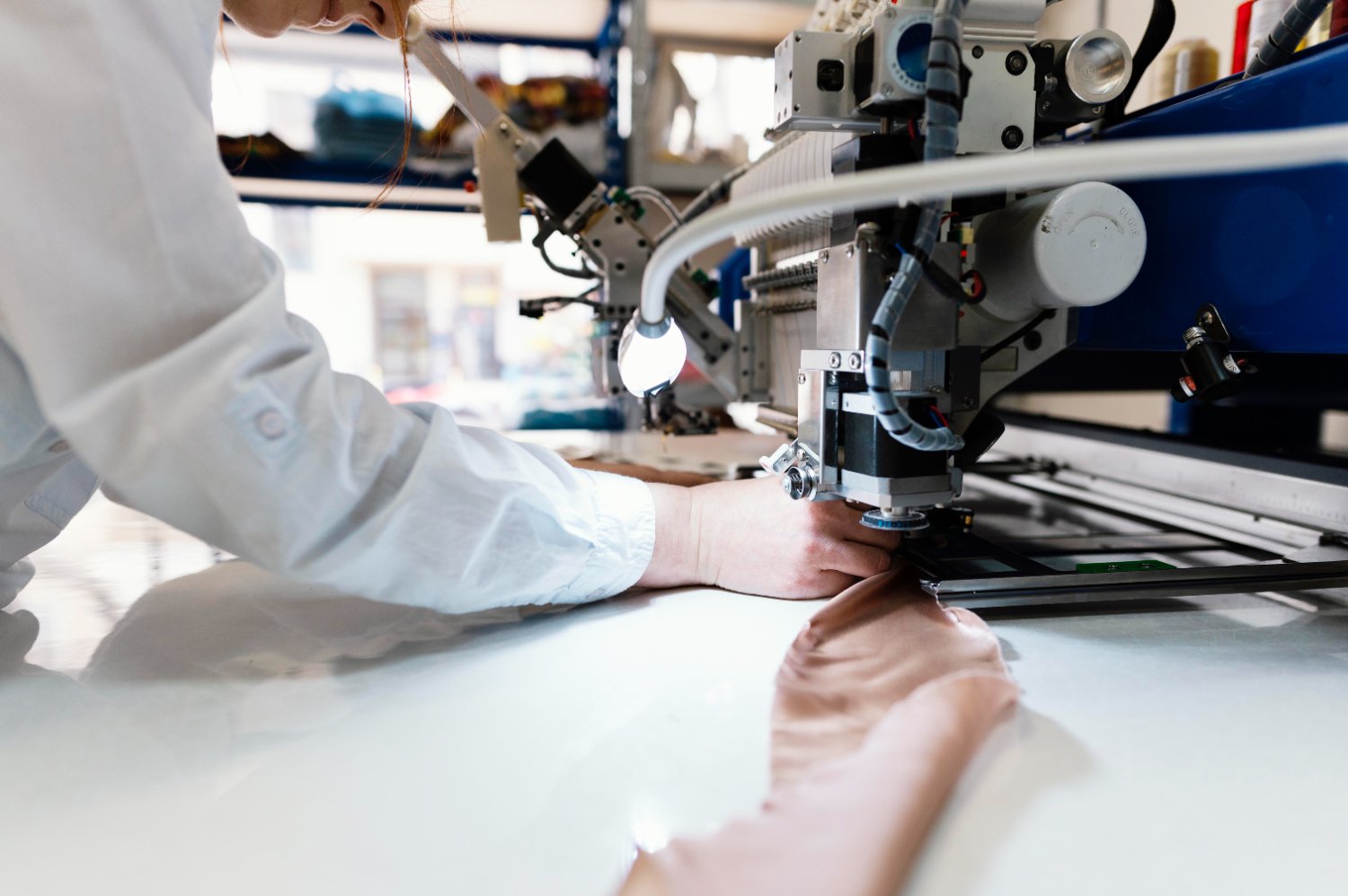 New Hampshire In the heart of a bustling manufacturing company, a person skillfully operates a sewing machine with brown fabric, showcasing precision and dedication in an industrial setting. Marketing Agency