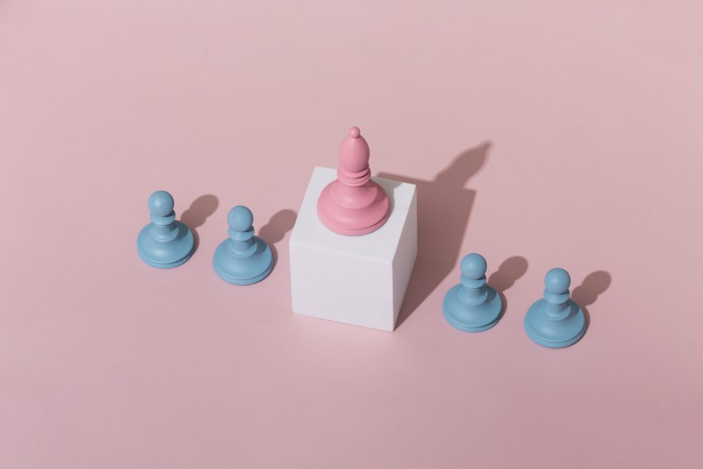 New Hampshire A pink chess bishop on a white cube stands amidst five blue chess pawns on a pink background. Marketing Agency