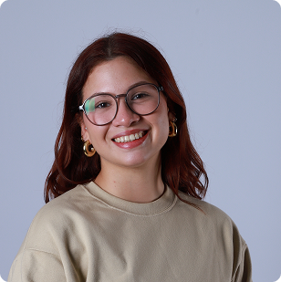 New Hampshire A young woman with shoulder-length brown hair, glasses, and gold hoop earrings smiles at the camera against a plain light background. She is wearing a beige sweatshirt. Marketing Agency