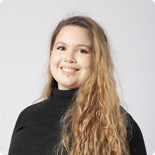 New Hampshire A woman with long wavy blonde hair wearing a black turtleneck sweater smiles at the camera against a plain light background. Marketing Agency