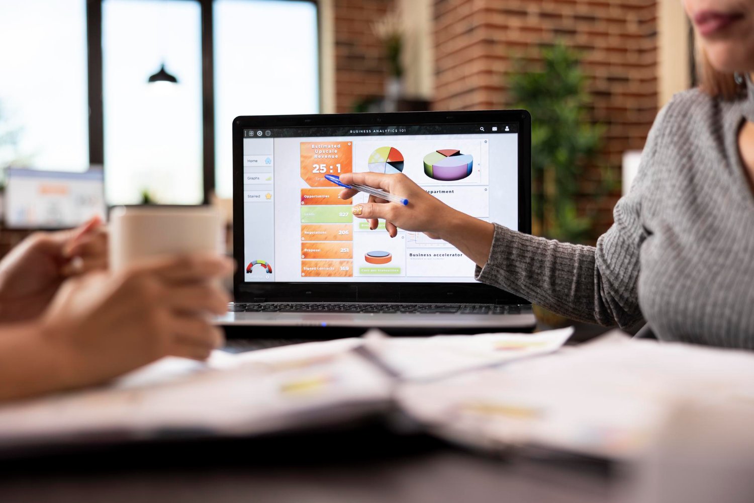 New Hampshire Two people sit at a desk discussing data, with one person pointing at charts and graphs displayed on a laptop screen. Marketing Agency