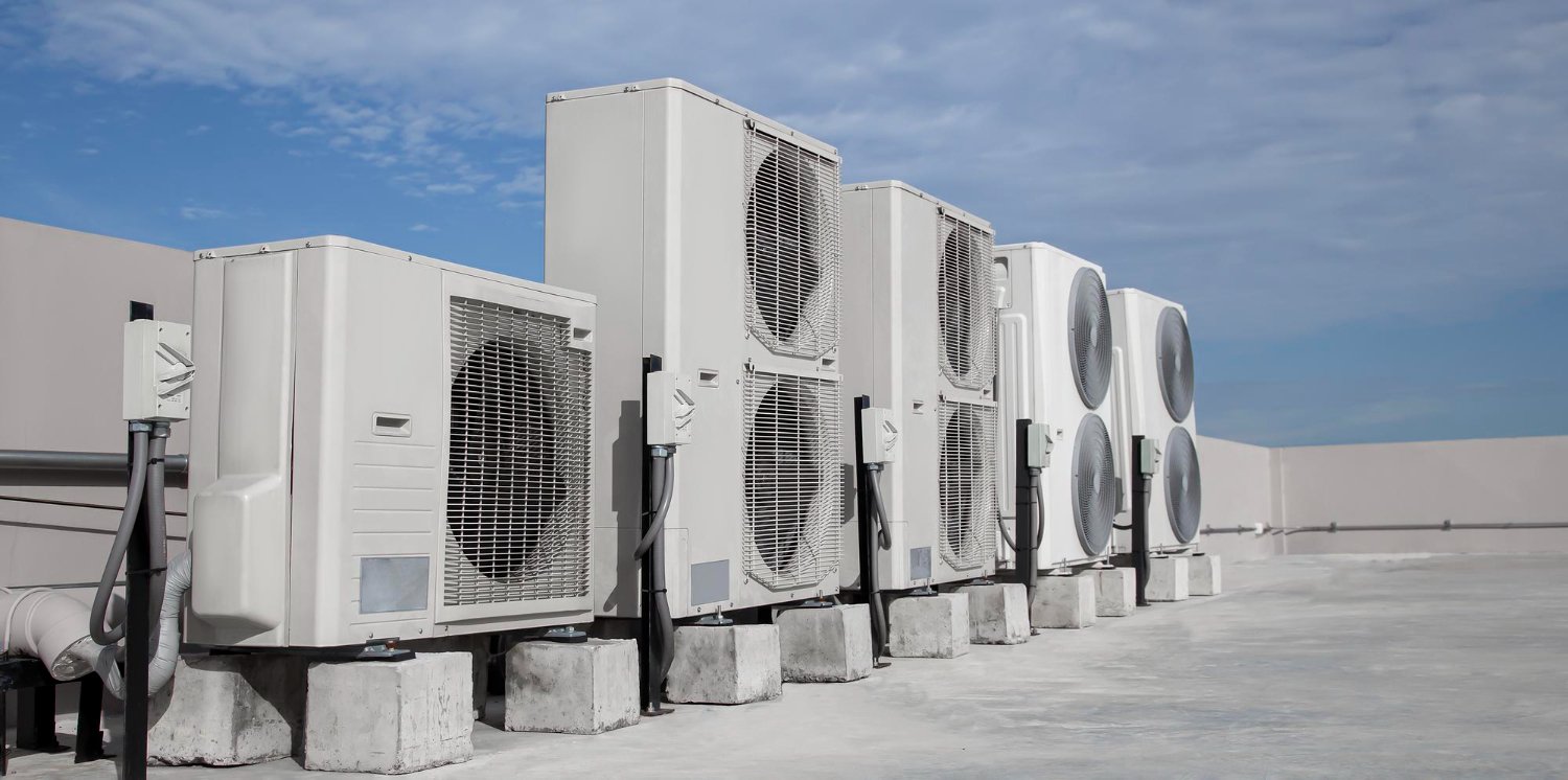 New Hampshire A row of outdoor air conditioning units is installed on concrete blocks on a flat rooftop under a clear sky. Marketing Agency