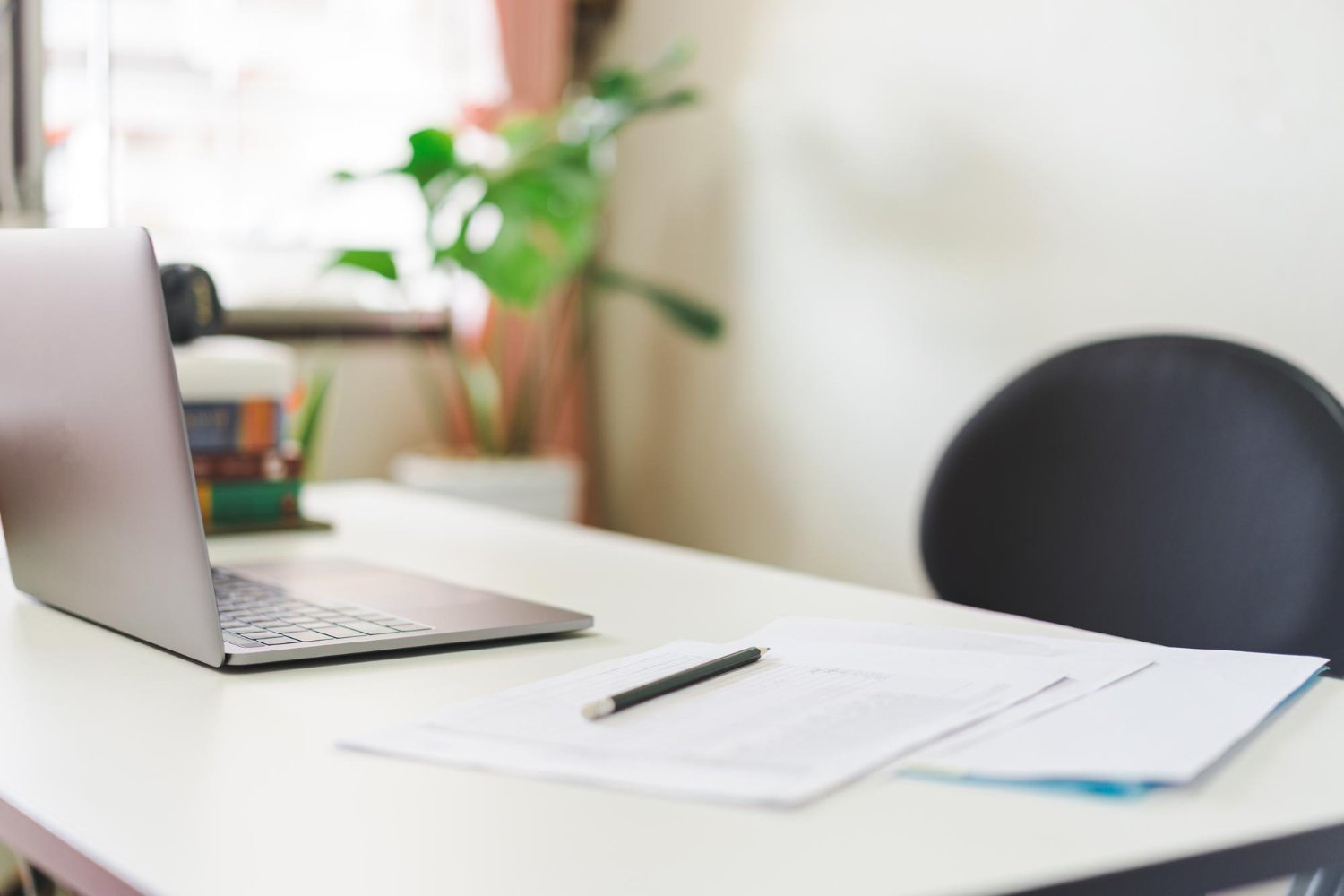 New Hampshire A laptop, documents, and a pen are on a white desk in a well-lit room with a plant and window in the background. Marketing Agency