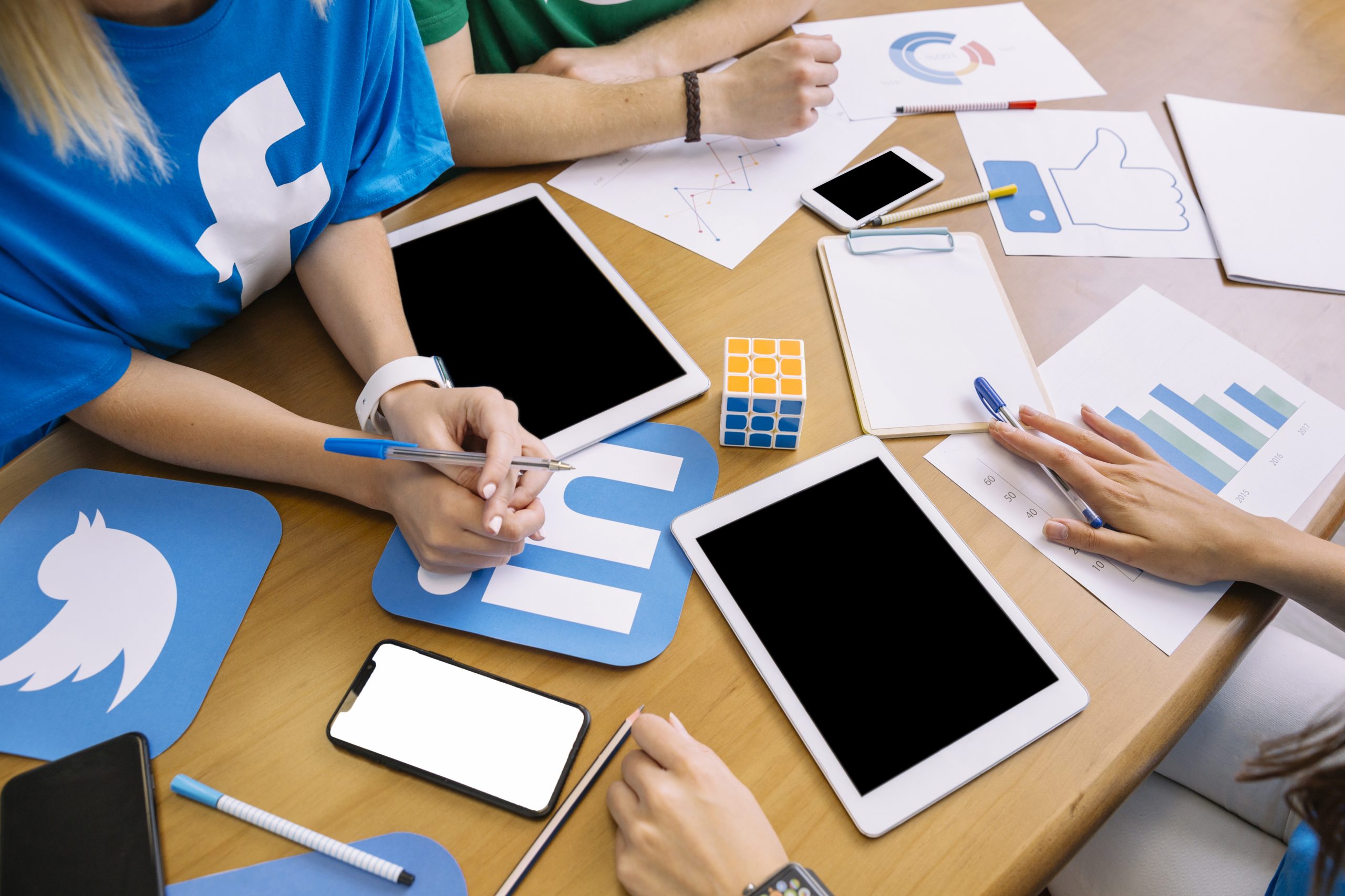New Hampshire People working at a table with tablets, smartphones, charts, and social network logos like Facebook and LinkedIn, discussing digital strategy for businesses in New Hampshire. Marketing Agency