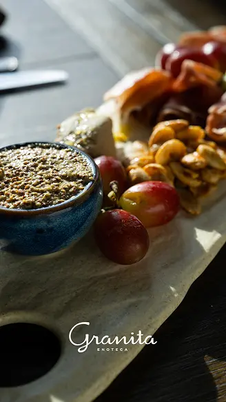 New Hampshire A charcuterie board with cured meats, grapes, nuts, cheese, and a small bowl of coarse mustard on a marble slab. The text "Granita Enoteca" appears at the bottom. Marketing Agency