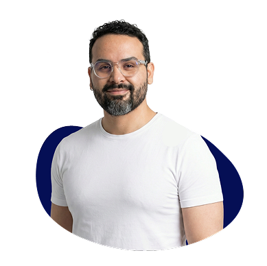 New Hampshire Man with short curly hair, beard, and glasses wearing a white t-shirt, standing in front of a white background with a blue abstract shape. Marketing Agency