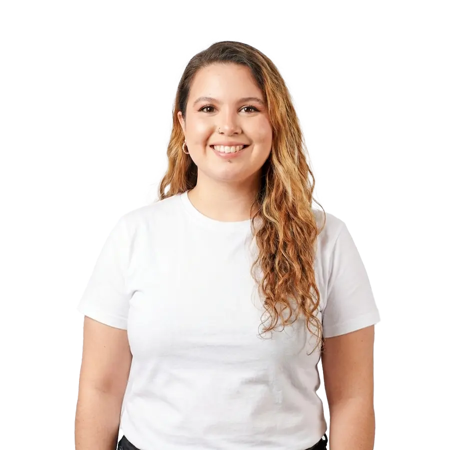 New Hampshire A woman with long wavy hair, wearing a white t-shirt, stands facing the camera and smiling against a plain background. Marketing Agency