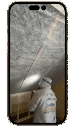 New Hampshire A person in protective clothing uses a tool to cut into an insulated ceiling, seen through the screen of a smartphone. Marketing Agency