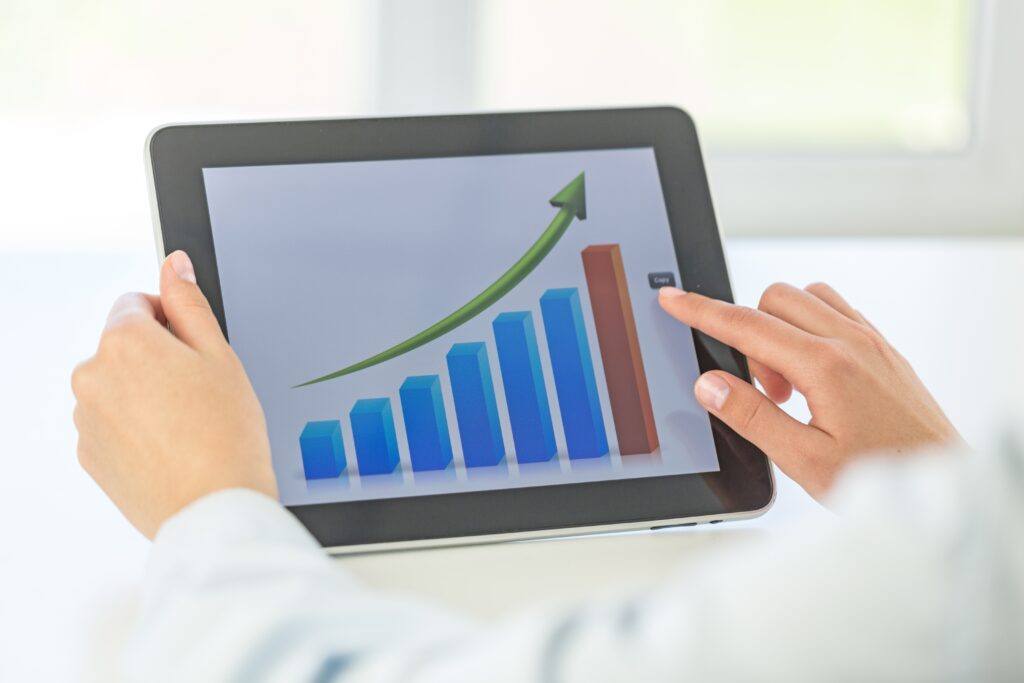 New Hampshire A person using a tablet displays a bar graph with blue bars and a rising green arrow, illustrating upward growth—perfect for showcasing lead generation or remarketing strategies for local businesses. Marketing Agency