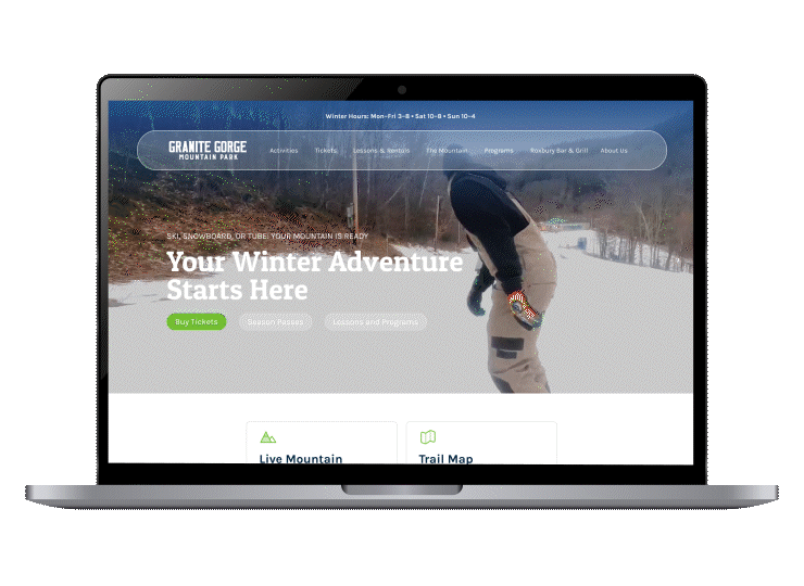 New Hampshire Laptop displaying a webpage for Granite Gorge Mountain Park with a winter sports theme and options to buy tickets or view mountain info. Marketing Agency